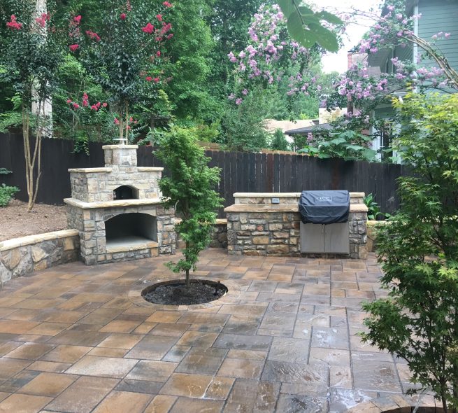 A stone patio with a tree planted in the middle, part of the landscape design and installation StoneAge Stonescapes does