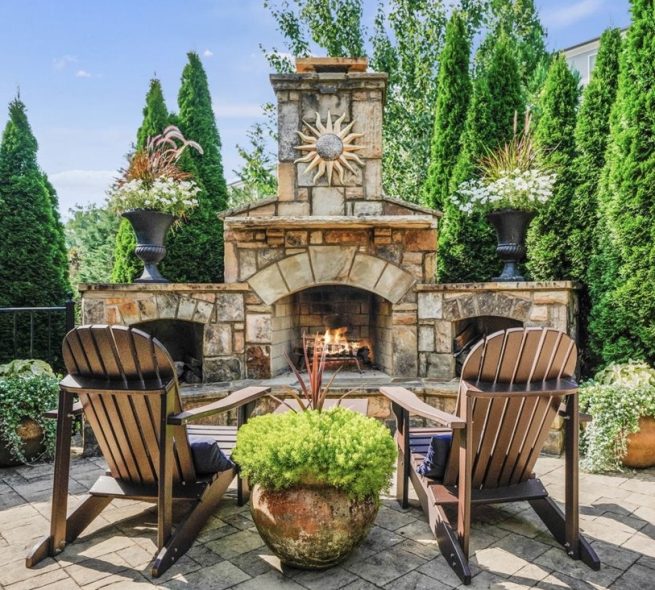 An outdoor fireplace with deck chairs near it, constructed by StoneAge Stonescapes